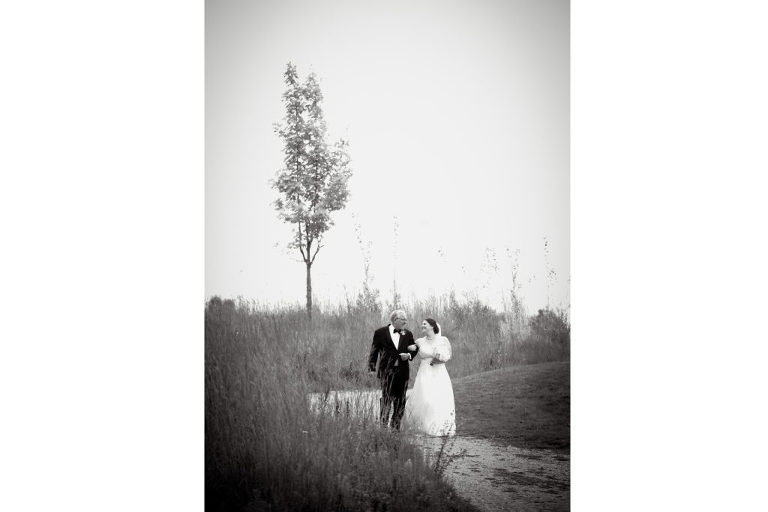 The bride and her father walk down the path to the ceremony site at the Indian Springs Metropark wedding in White Lake, Michigan.