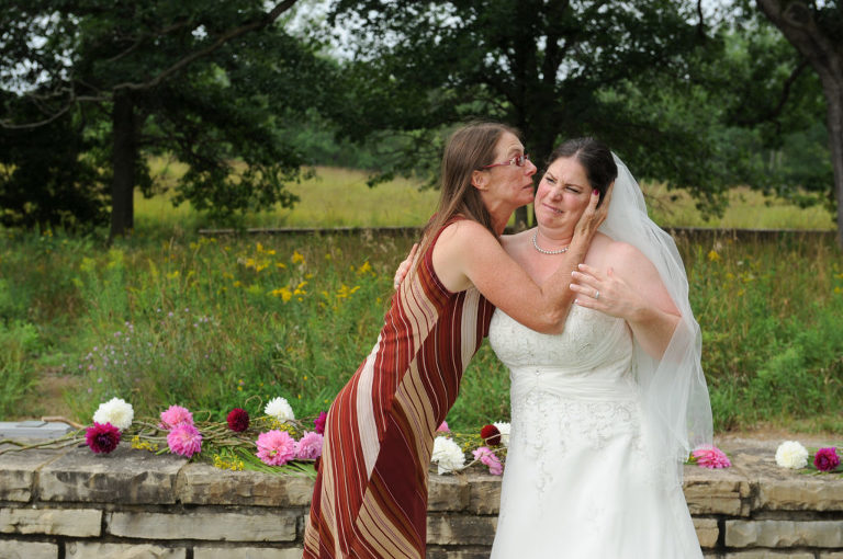 The bride gets a kiss from her sister after the wedding ceremony at the Indian Springs Metropark wedding in White Lake, Michigan.