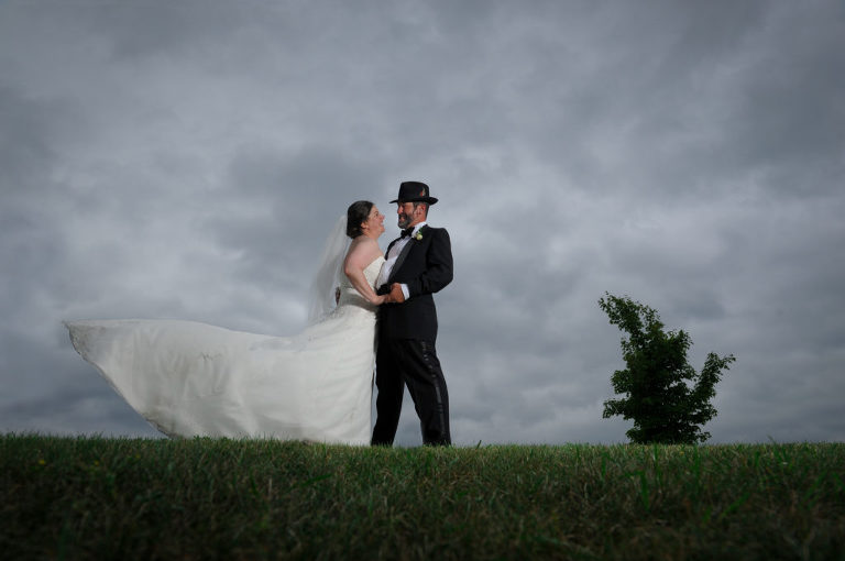 The bride and groom pose in the stormy looking weather after the wedding ceremony at the Indian Springs Metropark wedding in White Lake, Michigan.