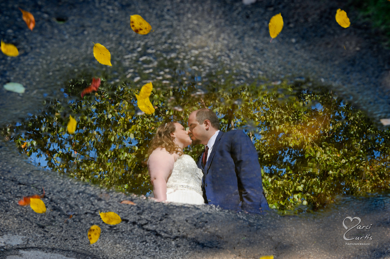 The bride and groom reflected in a puddle in the fall. Ypsilanti Freighthouse wedding photography of the newly renovated historic building in Depot Town, Ypsilanti, Michigan.