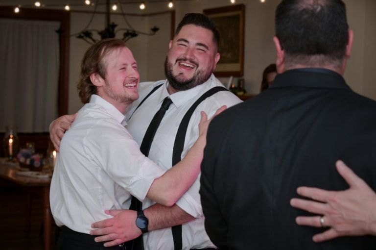 Two groomsmen dance together in a moment of levity at Greenfield Village in Dearborn, Michigan.