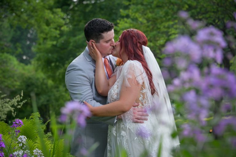 A bride and groom steal a kiss away from their guests during their Weller's wedding in Saline, Michigan.