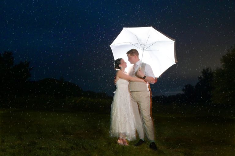 The bride and groom took photos in the rain after it rained all day in Essex, Vermont on their wedding day.