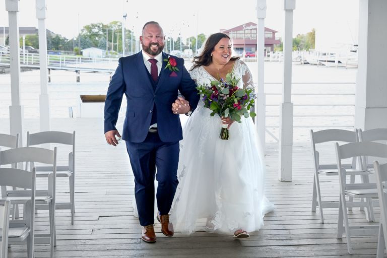 The groom joins the bride as they enter to large covered dock area at Roostertail for their wedding ceremony.