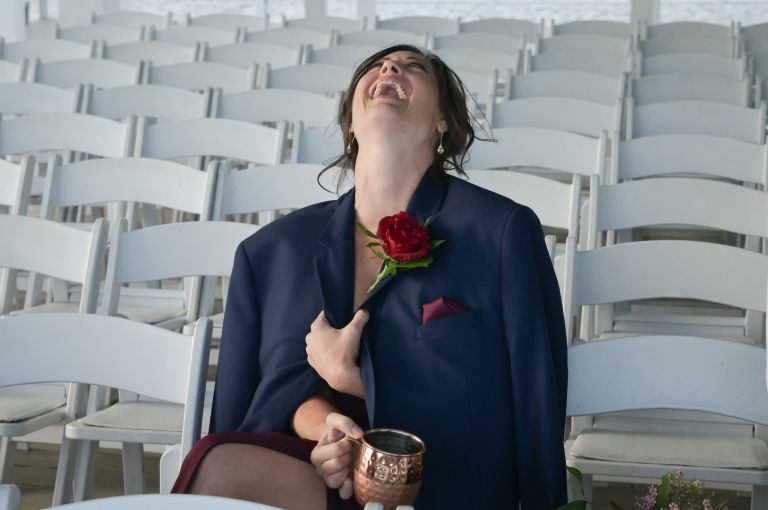 A cold guest laughs during formal photos at the top wedding venue, Roostertail in Metro Detroit, Michigan.