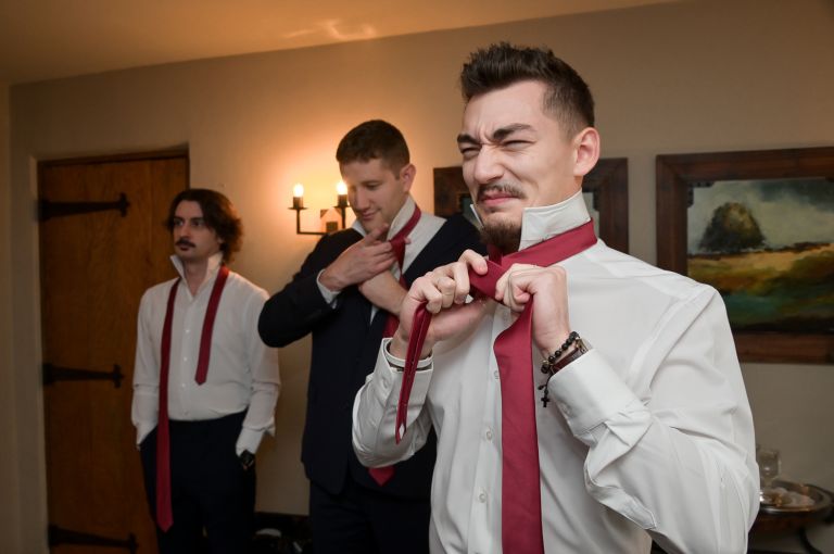 The best man struggles with his tie at a fall wedding at Addison Oaks Buhl Estates in Leonard, Michigan.