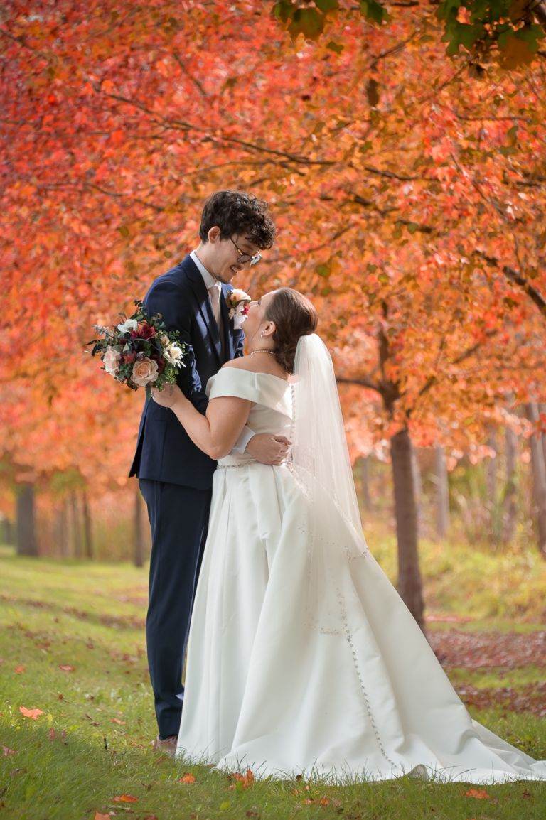 The bride and groom pose for photos during their fall wedding at Addison Oaks Buhl Estates in Leonard, Michigan.