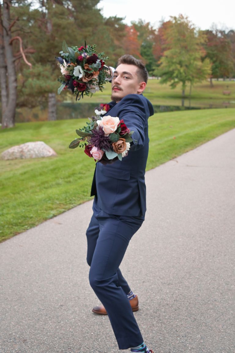 The best man playing with the bouquets during photos at Addison Oaks Buhl Estates in Leonard, Michigan.