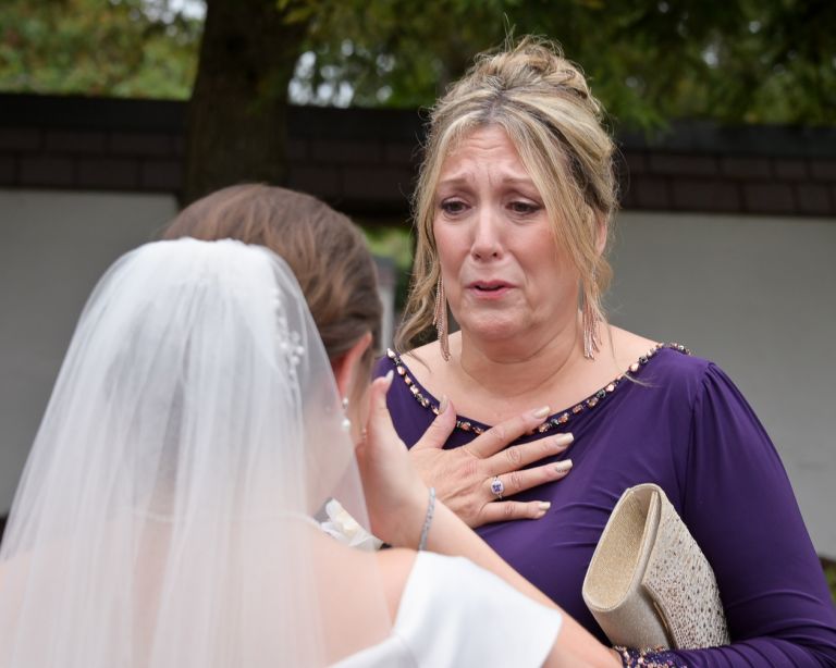 The groom's mother talking to the bride during cocktail hour after his fall wedding at Addison Oaks Buhl Estates in Leonard, Michigan.