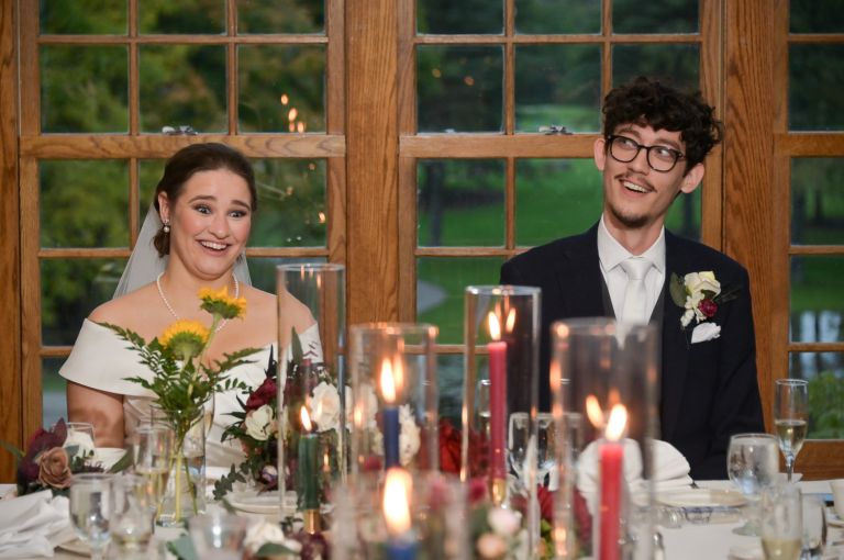 The the bride and groom's faces during speeches after their wedding at Addison Oaks Buhl Estates in Leonard, Michigan.