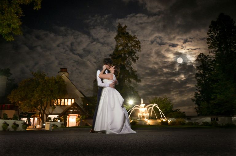 The bride and groom pose for photos at the fountain after their fall wedding at Addison Oaks Buhl Estates in Leonard, Michigan.