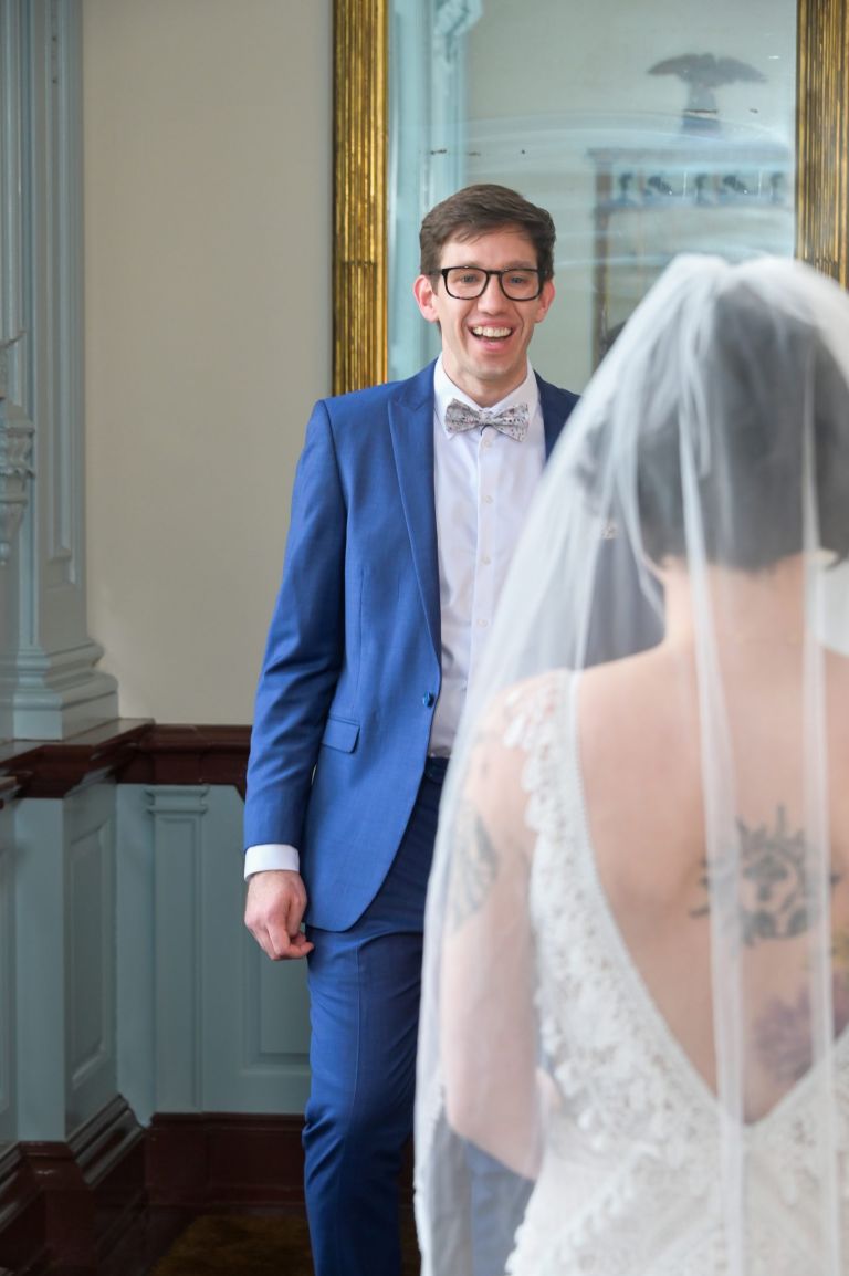 The groom sees his bride for the first time during their first look at the Henry Ford Museum in Dearborn, Michigan.