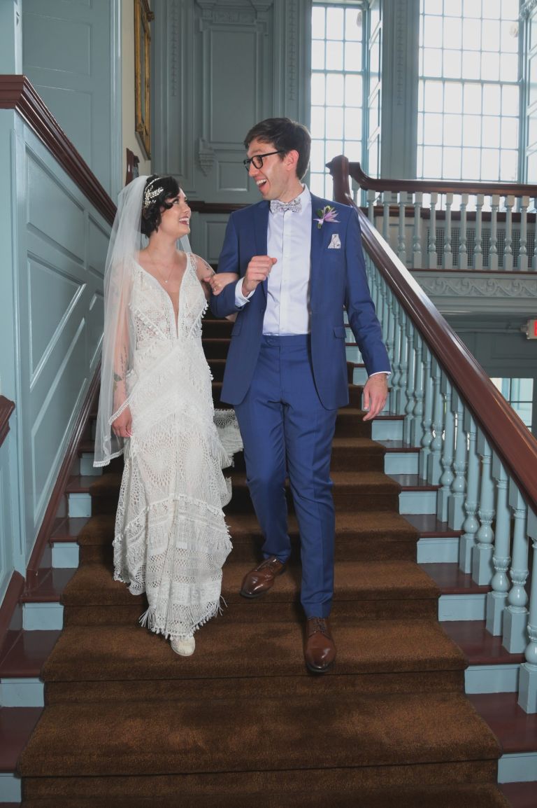 The bride and groom head down the stairs to meet the rest of the wedding party at the Henry Ford Museum in Dearborn, Michigan.
