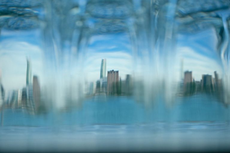 A photo of the Windsor skyline through glasses lined up at the bar at Detroit's Waterview Loft wedding venue.