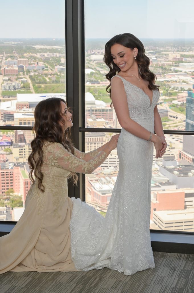 The bride's mother helps button her into her dress at the hotel.