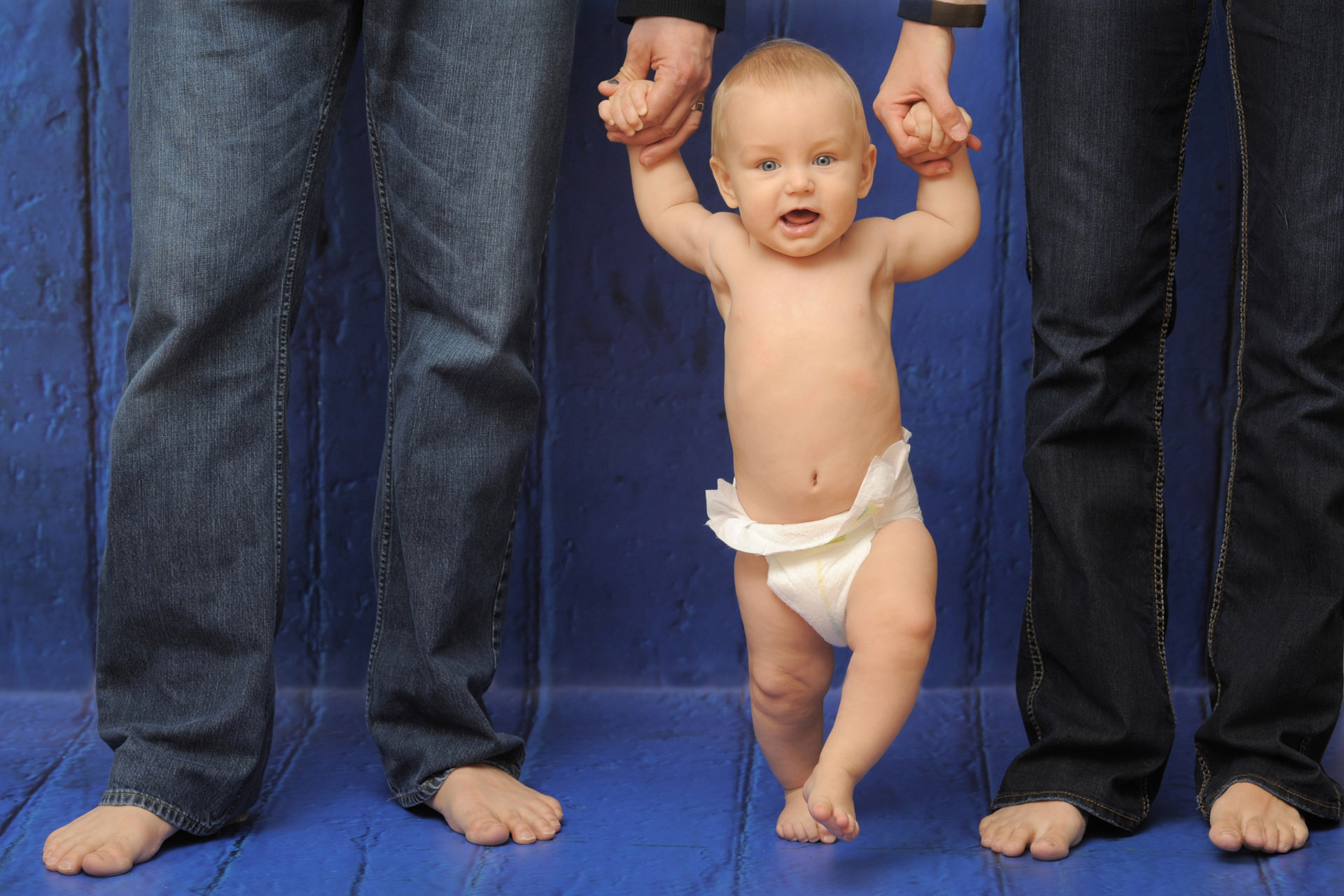 Best Detroit childrens photographer photographs a young child standing between his parents in Troy, Michigan.