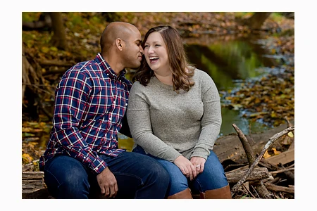 An engaged couple smooch during a fall engagement photo session in Troy, Michigan.
