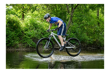 A Stoney Creek senior does a jump in a river near Rochester, Michigan for his senior pictures with his mountain bike.