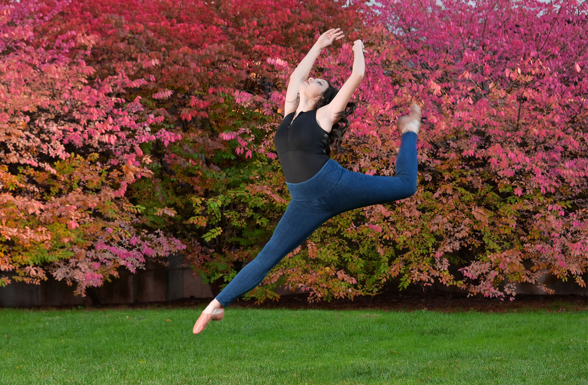 Olivia flies high with an energetic leap with Michigan fall colors behind her. 